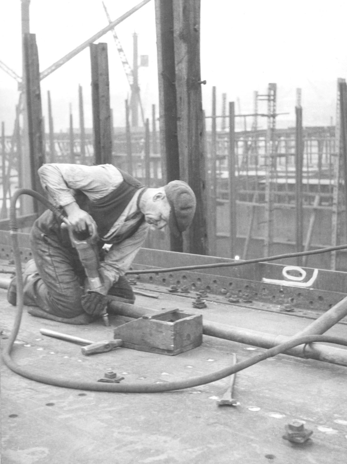 black and white photo of a shipyard worker using a rivet gun